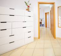 A hallway with a white dresser, built-in mirror, and tiles in a 3-room apartment.