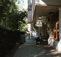 Sidewalk on Záhradnícka Street in Bratislava with shops and people.