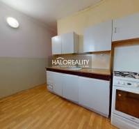 A kitchen in a 3-room apartment with a white kitchen unit and a floor with a wood design.