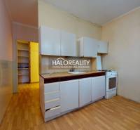 A kitchen in a 3-room apartment with a wooden decor floor and white cabinets.