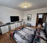 A bedroom in a 3-room apartment with a television, a white dresser, and a wooden decor floor.