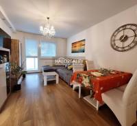 Living room of a three-room apartment with a wood-patterned floor and a dining table.