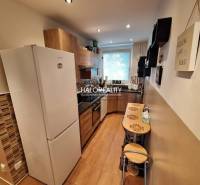 A kitchen in a 3-room apartment with a wooden decor floor and a dining area.
