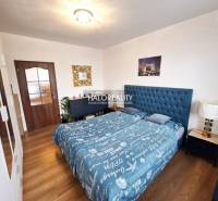 A bedroom in a 3-room apartment with a patterned bed and a wooden decor floor.