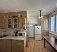 A kitchen in a 2-room apartment with a wood-patterned floor, light cabinets, and a table.