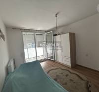 Interior of a 2-room apartment with a bed, wardrobe, and floor with wooden decor.