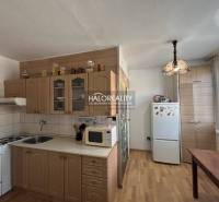 A kitchen in a 2-room apartment with a kitchen unit, refrigerator, and floor with a wooden decor.