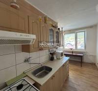 A kitchen in a 2-room apartment with a wooden decor floor and a view from the window.