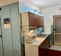 A kitchen with wooden cabinets and white appliances in a 4-room apartment.
