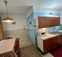 Dining room with a table and kitchen in a 4-room apartment, equipped with cabinets and appliances.
