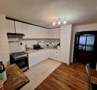 A kitchen in a family house with white cabinets and a wood-patterned floor.