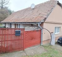A family house in Brestovany with a tiled roof, a red fence, and a driveway.