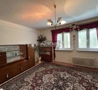 A room with older furniture, a chandelier, a carpet, red curtains, a family house.