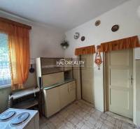 A kitchen in a **family house** with vintage furniture, orange curtains, ceramic decorations.