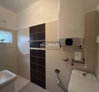A bathroom in a family house with a sink, faucets, and an electric boiler on the wall.