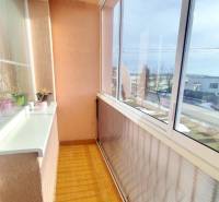 Glazed loggia in a 3-room apartment with ceramic tiles and a view of the exterior.