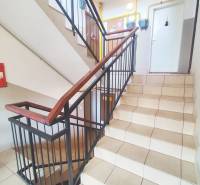 A staircase with tiles and metal railing leading to apartments in the building.