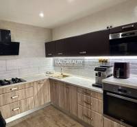 A kitchen in a 3-room apartment with a wooden decor and a white brick wall cladding.
