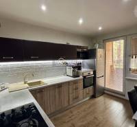 A kitchen with a wooden decor floor in a 3-room apartment, equipped with modern appliances.