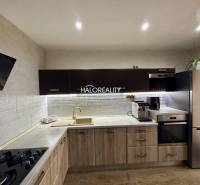 A kitchen in a 3-room apartment with white brick tiles and a wooden decor floor.