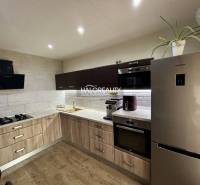 A kitchen in a three-room apartment with a wooden decor floor and appliances.