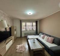 Living room in a three-room apartment with a wooden decor floor and a comfortable sofa chair.