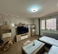 Living room with seating, wood-patterned flooring, television, and decorative wall in a 3-room apartment.