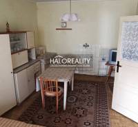 Rustic kitchen with a wooden cabinet, dining table, and television in a family house.