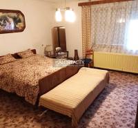 A bedroom with an antique bed, curtains, a painting, and a carpet. The family house offers a cozy space.