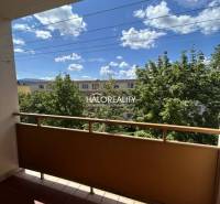The balcony of a 3-room apartment in Prievidza with a view of trees and the sky.