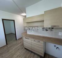 A kitchen in a 3-room apartment with wooden flooring and furniture.