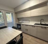 Kitchen in a three-room apartment with a wooden decor floor and a dining table.