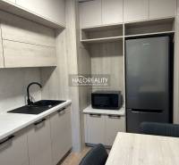 A kitchen in a 3-room apartment with a wooden decor floor, gray cabinets, and appliances.