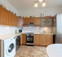 A kitchen with built-in doors, appliances, and a dining table in a two-room apartment.