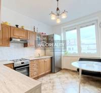 A kitchen in a 2-room apartment with built-in appliances and a dining table.