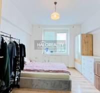 Bedroom with a bed, wardrobe, and dresser in a 2-room apartment with a wooden decor floor.