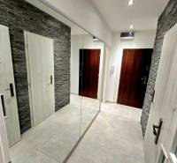 A hallway in a 2-room apartment with tiles, stone cladding, and a large mirror.