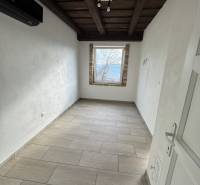 A narrow window in the attic complements the ceiling with wooden beams.