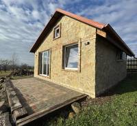 Stone cottage in Šahy with a terrace, surrounded by nature and a blue sky.