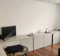 Living room in a family house with a TV, practical storage space, and a floor with a wooden decor.
