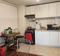 A kitchen with white cabinets and a wood-patterned floor in a family house.