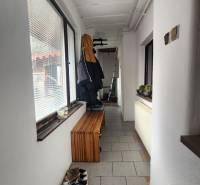 A narrow hallway with tiles, a bench, and a coat rack in a family house.
