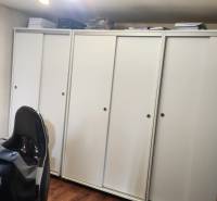 A room in a family house with white cabinets, a gaming chair, and a wooden decor floor.