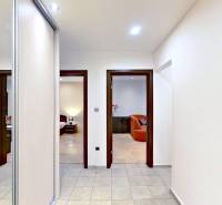 A hallway in a 2-room apartment with tiles, mirrors, and visible rooms with wood-patterned flooring.