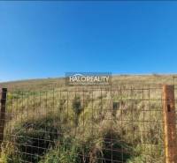 A fenced residential plot in Partizánske with a wire fence under a blue sky.