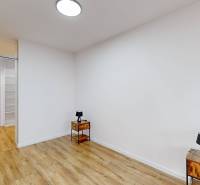 A room in a family house with a wooden decor floor and an entrance to the toilet.
