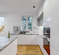 A kitchen in a family house with a marble countertop and a floor with a wooden decor.