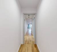 A hallway with white walls and a wooden decor floor in a family house.