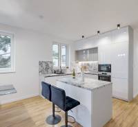 A kitchen in a family house with a wood-patterned floor and light-colored furniture.