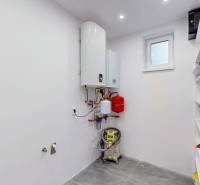 Technical room with a boiler and shelves in a family house.